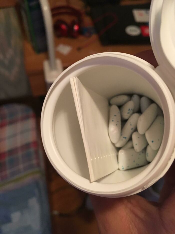 Container with white tablets and a folded note, a cool product with surprises inside.