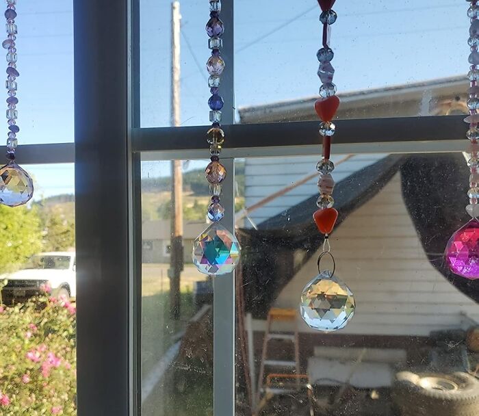 Hanging crystal prisms and beads creating Dopamine Decor effects in sunlight through a window.