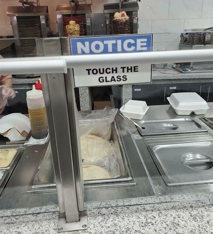 Confusing notice at a food counter instructs to touch the glass, showcasing unfortunate public interior designs.