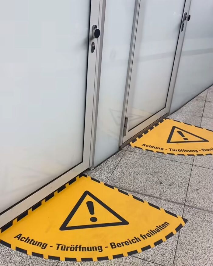 Warning signs on the floor in front of unclear glass doors represent unfortunate public interior designs.