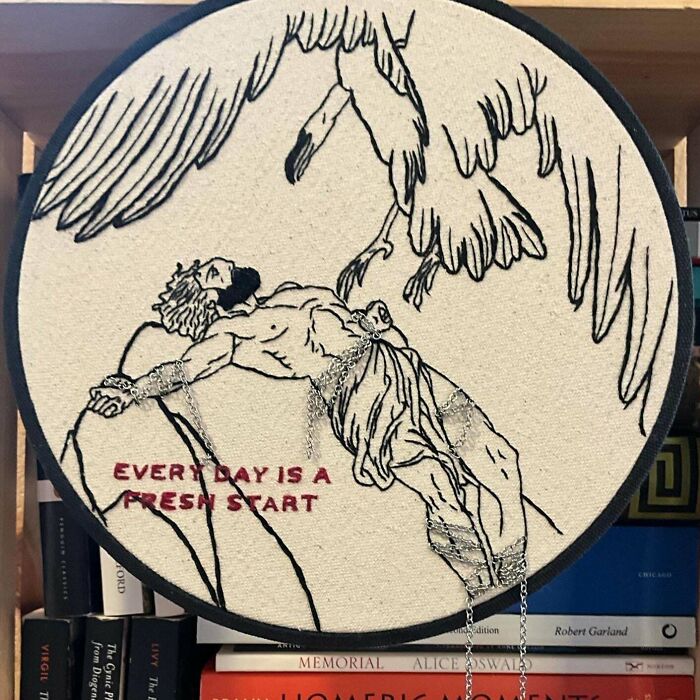 Embroidery design featuring a man and abstract wings with chains and text embroidered on fabric.