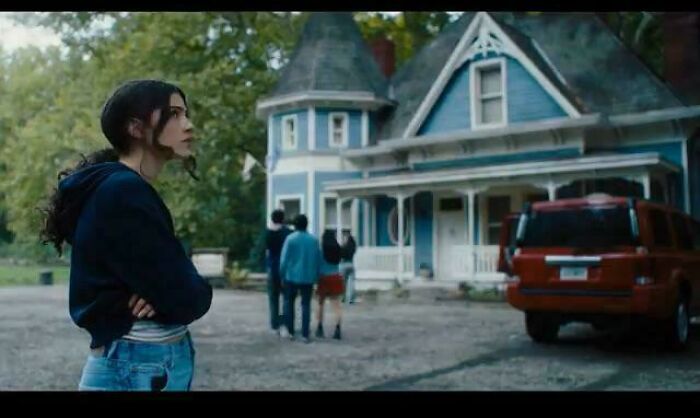 Young woman and group in front of a blue Victorian house, depicting questionable movie details that cinephiles mock online.
