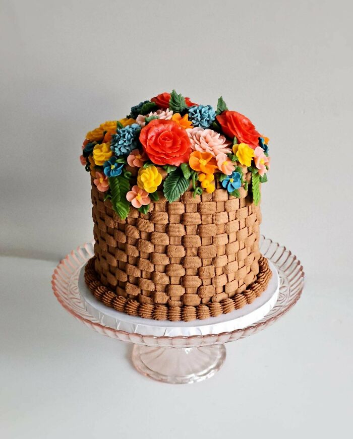 Intricately decorated cake with woven icing and colorful floral designs, showcasing exceptional baking artistry.