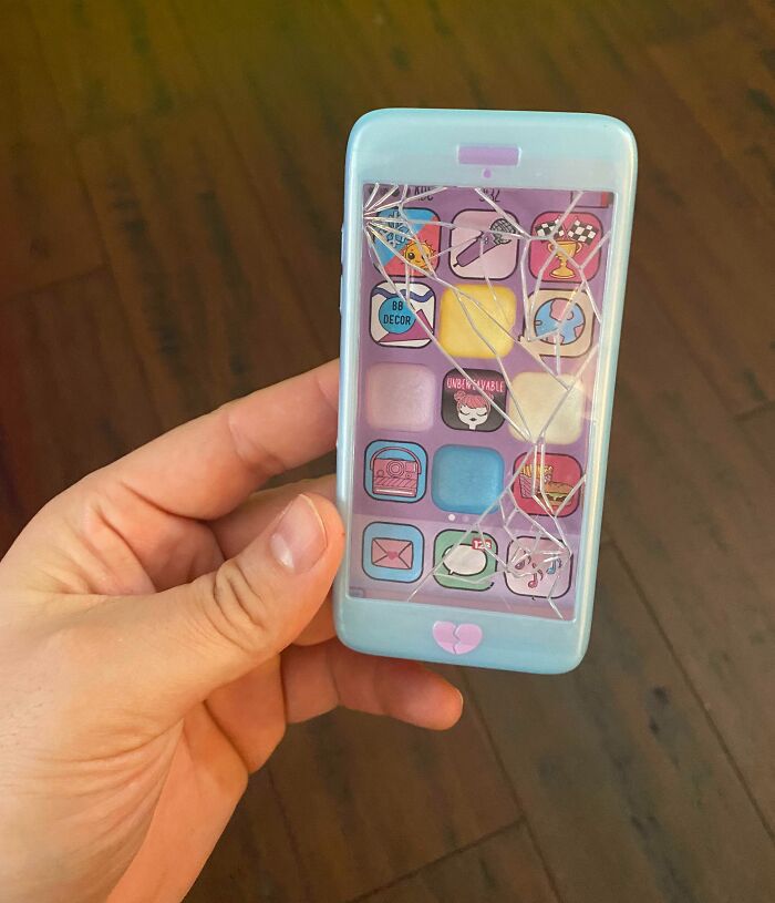 Hand holding a toy smartphone-shaped mirror with a c*****d screen, a cool product with surprises.