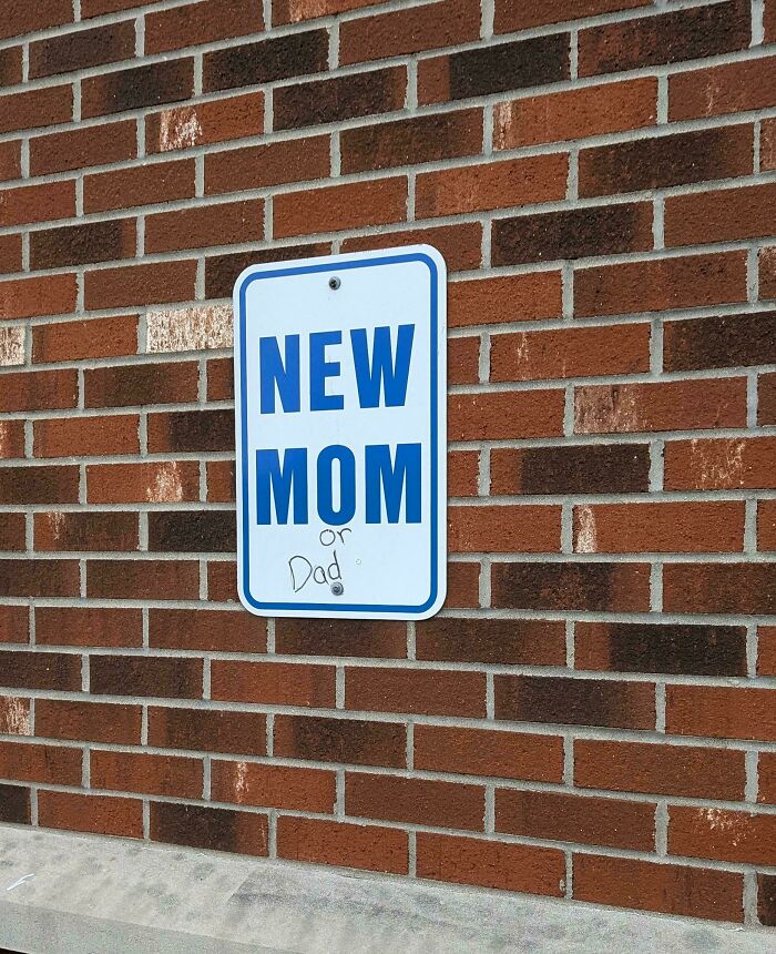 Sign on brick wall reading "New Mom or Dad," highlighting rewarding job of being a dad.