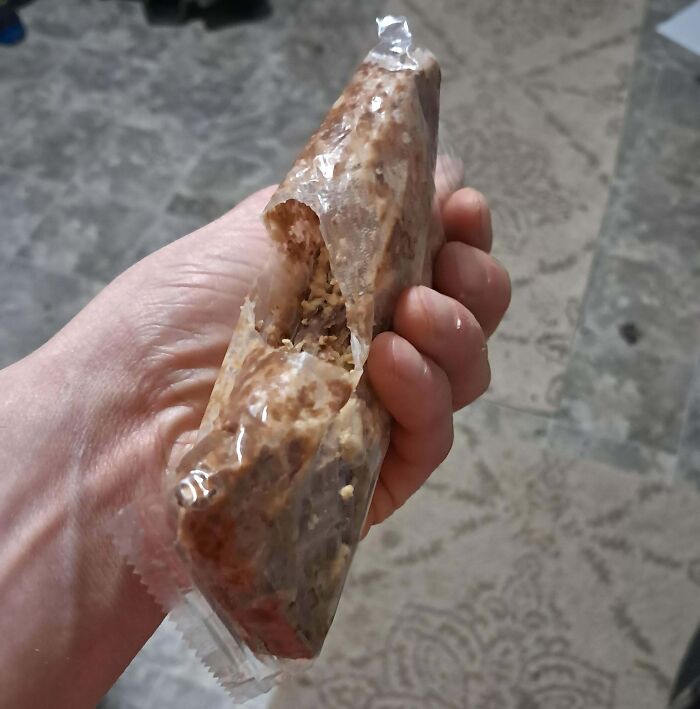 Hand holding a partially unwrapped chocolate bar, representing a dumb-clueless moment.