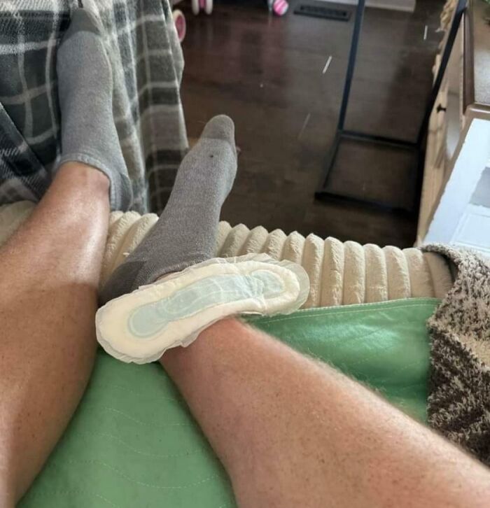 Pierna con calcetín y una compresa adherida, escena divertida de niño compartida por padres.