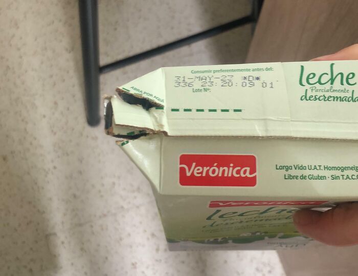 Damaged milk carton with visible expiration date and brand label, depicting a potentially clueless error in handling.