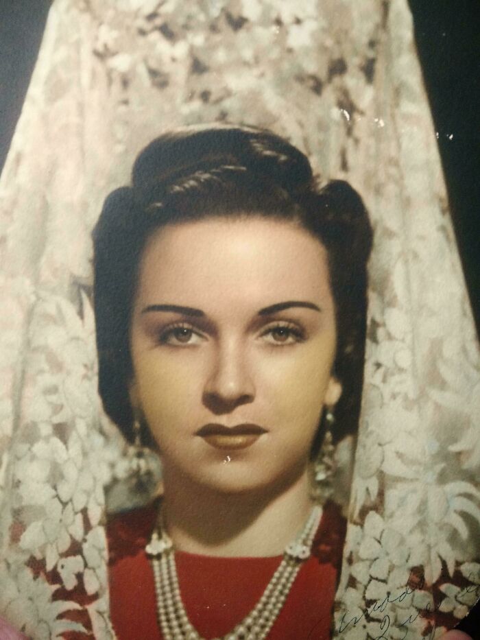 Woman in 1940s attire with red dress and lace veil, showcasing elegant vintage style.