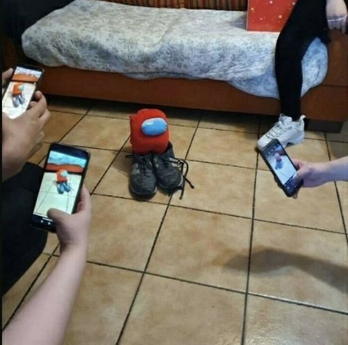 Three people taking photos of a stuffed toy among shoes on floor, showing a weird side of the internet scene.