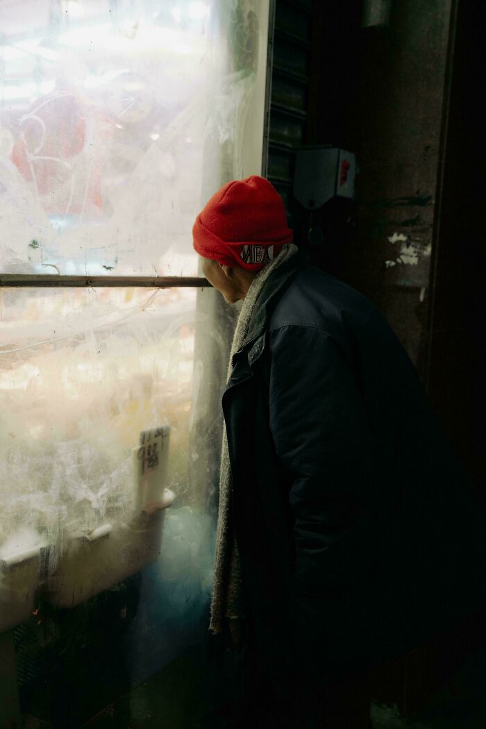 Person in red beanie gazing through a frosted window, evoking an accidental Renaissance painting feel.
