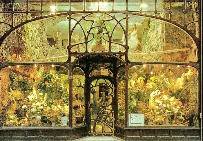 Art Nouveau architectural façade with intricate ironwork and lush floral displays in a beautifully designed storefront.