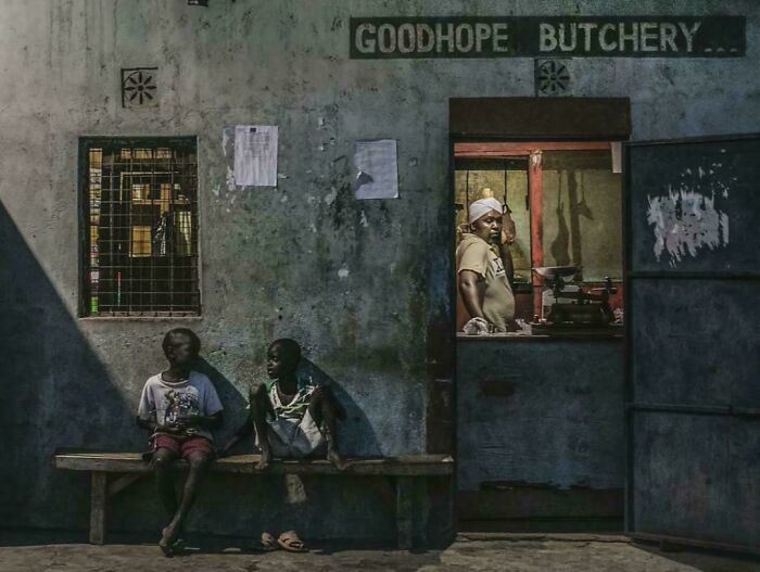 Two children sit outside a "Goodhope Butchery," creating an accidental Renaissance-style scene.