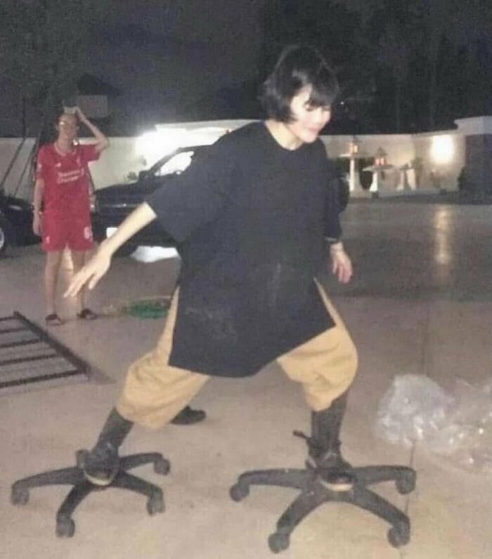 Person balancing awkwardly on two office chair bases outside at night, showcasing weird side of the internet humor.