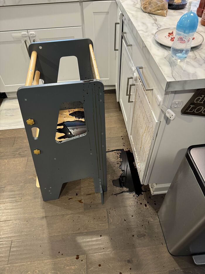 Spilled liquid in a kitchen with a toddler step stool, showing a light-hearted dad moment in parenting.