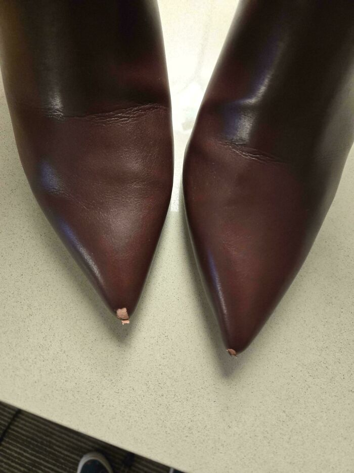 Worn-out brown leather shoes with scuffed tips, highlighting a critique of consumerism.