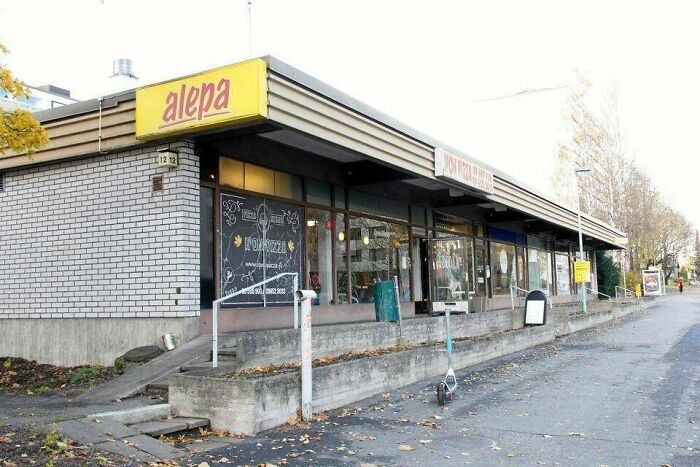 A small, rundown urban supermarket with overcast skies, symbolizing urban hell.