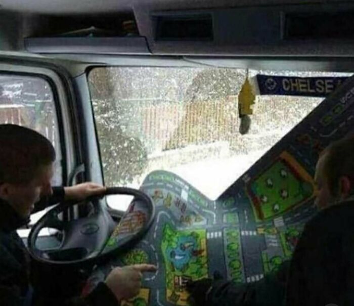 Two men inside a vehicle using a colorful play mat as a confusing road map, illustrating random photos processing challenges.