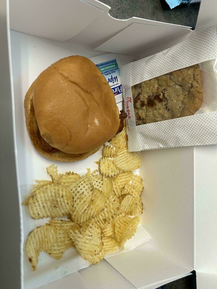 A disappointing company gift box with a plain burger, chips, and a cookie.