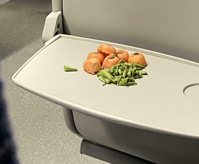 Carrots and beans placed on a train seat tray by funny subway passengers.