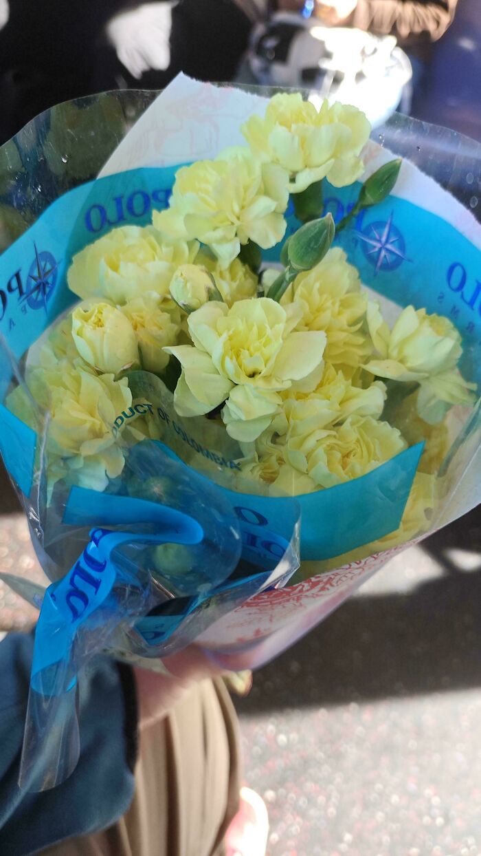 A bouquet of yellow flowers held in a person's hand, suggesting awkward-date-moments.