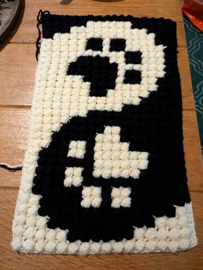 Black and white crochet masterpiece featuring a yin-yang design displayed on a wooden table, showcasing crochet art.