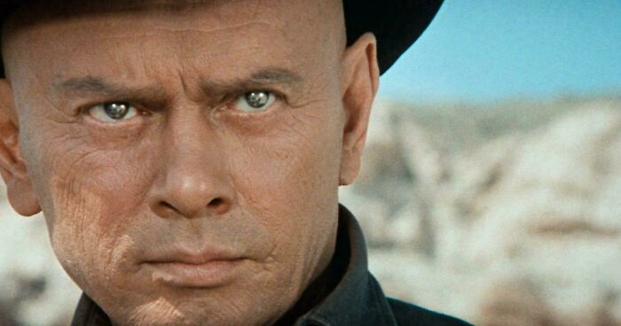 Close-up of a bald man with intense eyes wearing a hat, evoking childhood memories from the past.