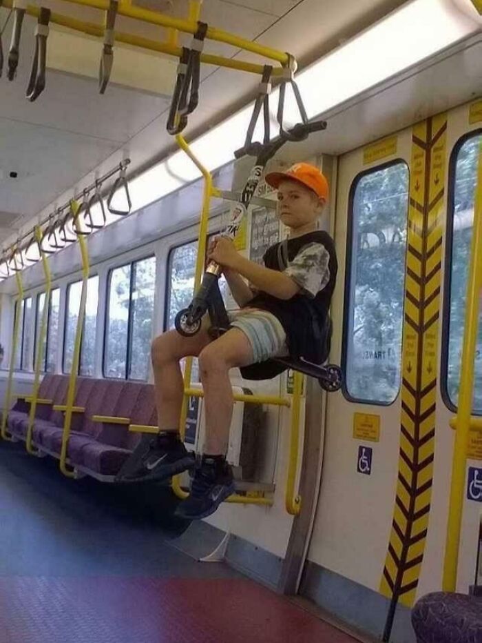 Young passenger amusingly hangs on a subway train while sitting on a scooter, showcasing funny train antics.