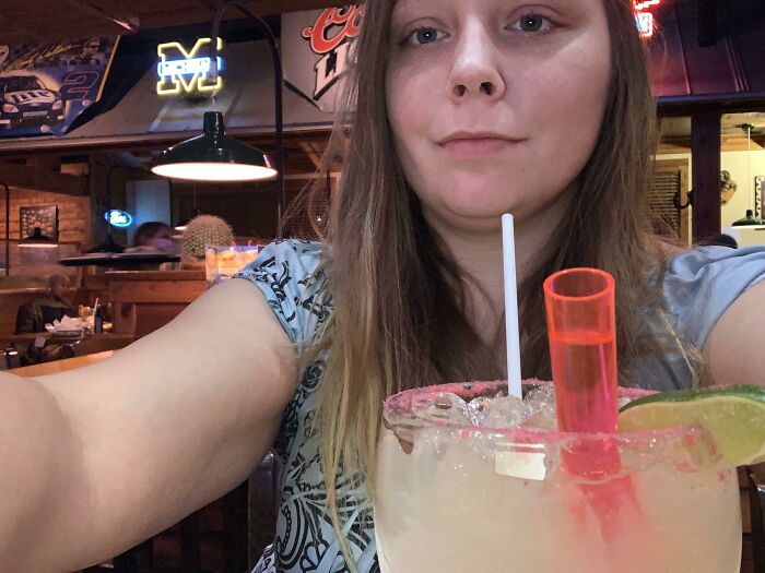 Woman at a bar with a large cocktail, capturing an awkward date moment.