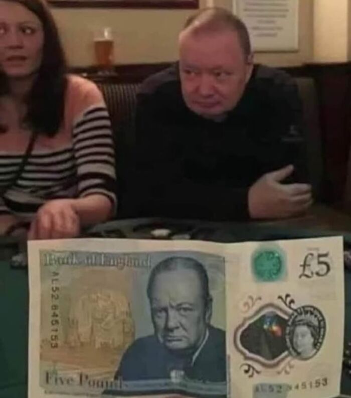 British five-pound note featuring Winston Churchill, with two people in a pub setting in the background.