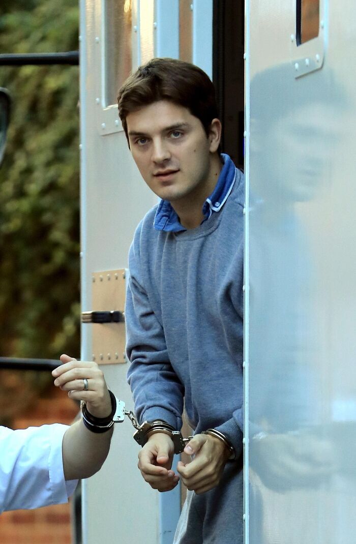 Handcuffed man exiting a vehicle, related to true crime stories and curiosities.