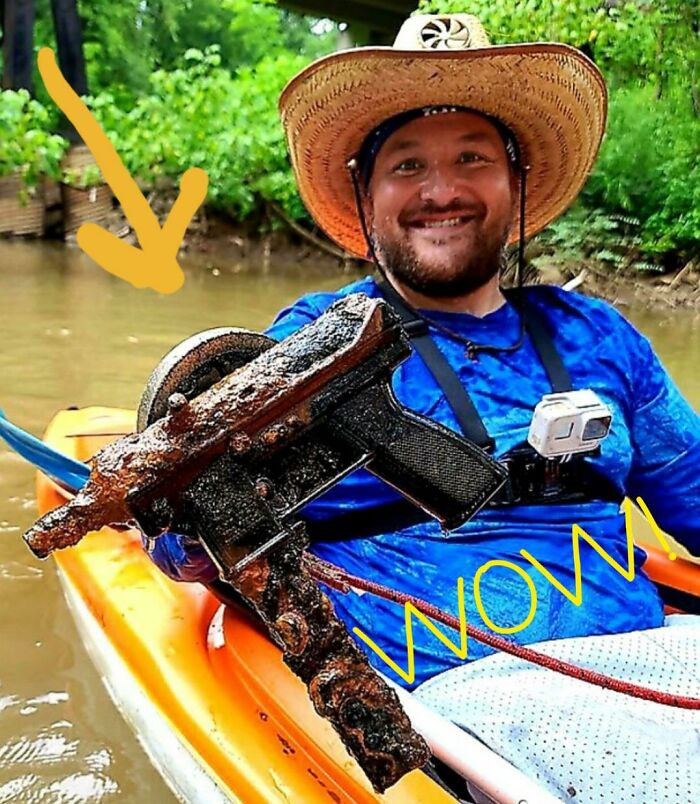 Man in a kayak holds a rusty gun found while exploring, highlighting true crime curiosities.