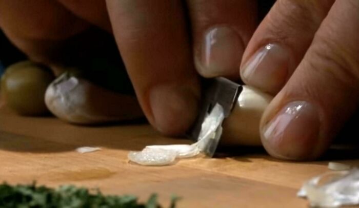 Close-up of hands peeling garlic with a knife highlighting questionable movie details mocked by cinephiles online.