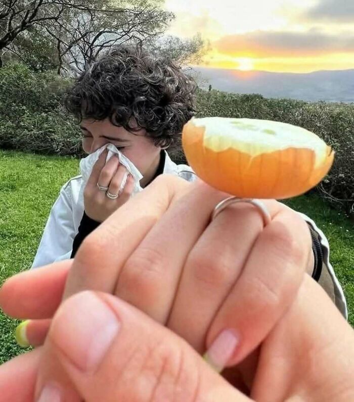 Person wiping tears while another hand holds a peeled onion slice, illustrating random photos processing challenges outdoors.