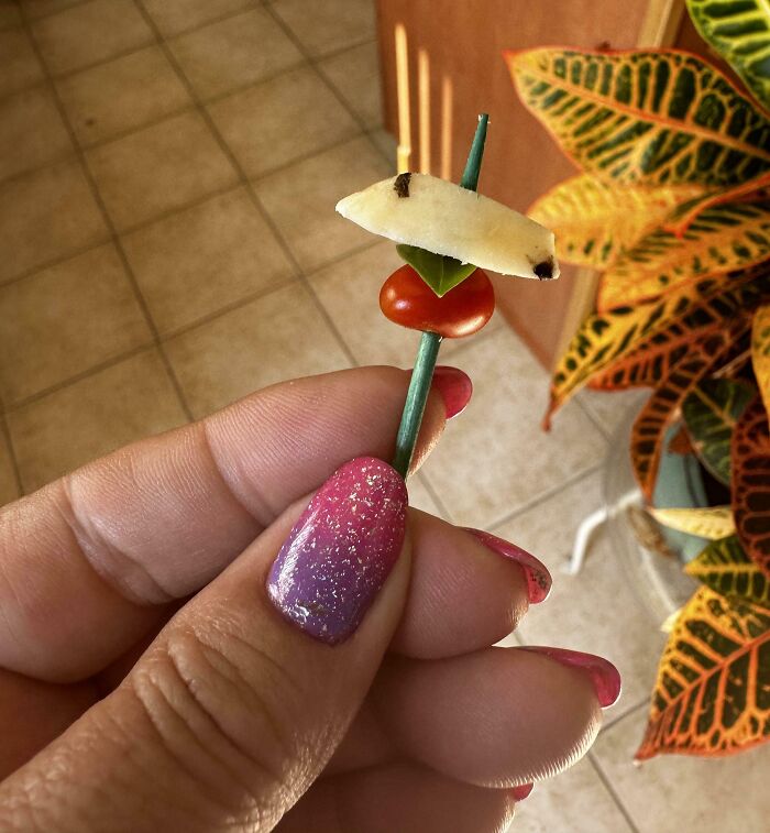 Hand holding tiny fruit and vegetable skewer in a gardening attempt.