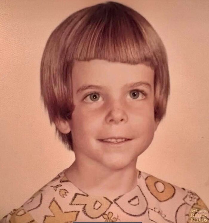 Child with a vintage awkward family photo hairstyle, wearing a patterned shirt, smiling sweetly for the camera.