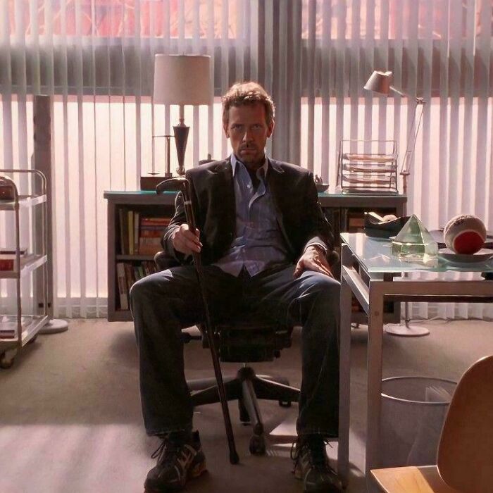 Man sitting in office chair holding cane with questionable movie details that cinephiles mocked in the background setting.