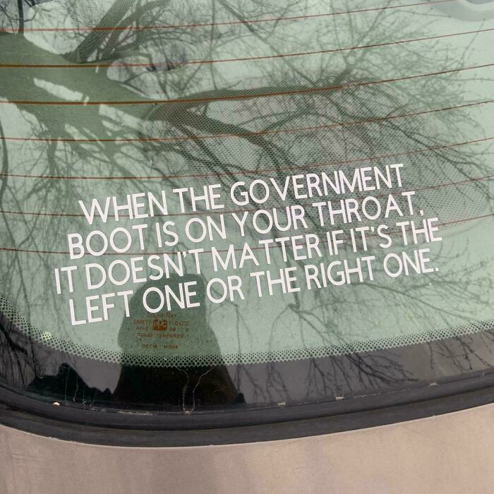Car with a funny bumper sticker about government on its rear window.