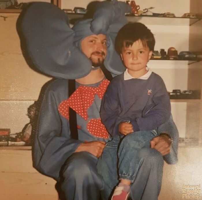 Man dressed in an elephant costume holding a child, sharing an awkward family photo that feels incredibly sweet and nostalgic.