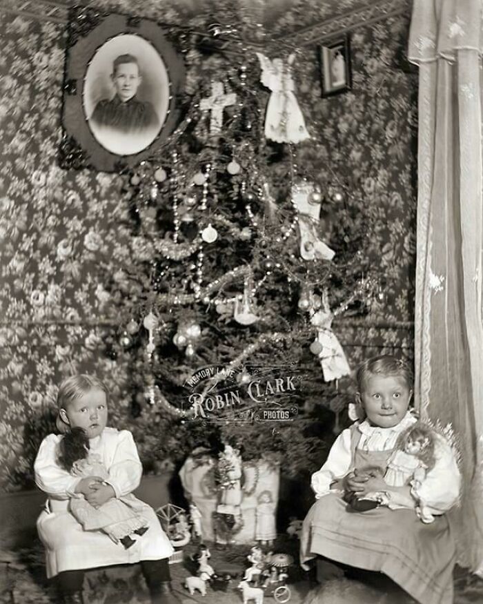 Children with dolls by a decorated Christmas tree in a vintage room, showcasing historical living decades ago.