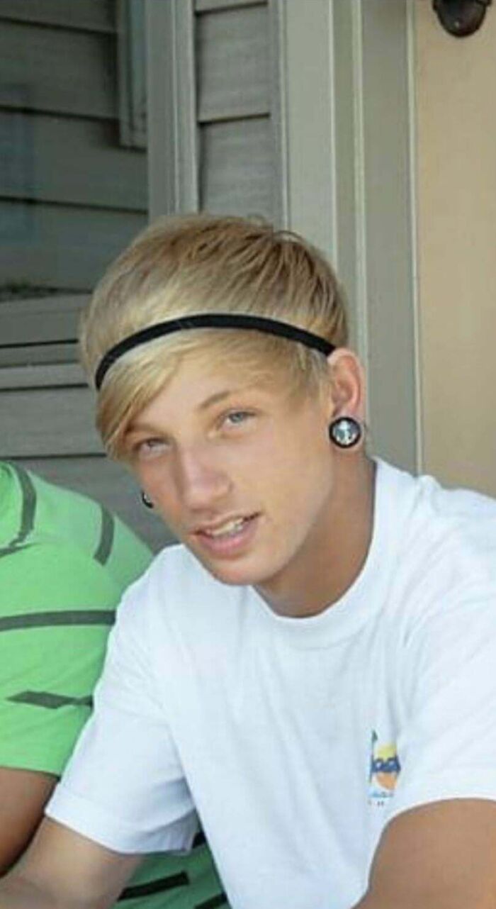 Teen with gauged ears and a headband during blunder years, wearing a white shirt, sitting outdoors.