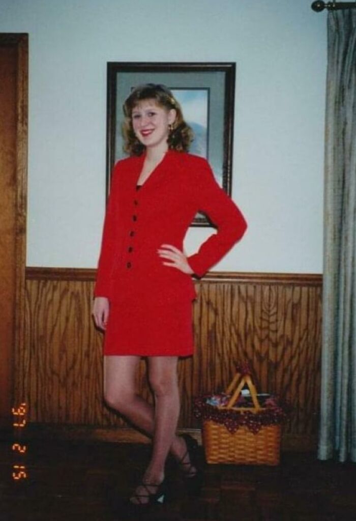 Vintage photo of a person in a red suit from their blunder years, standing indoors near a basket.