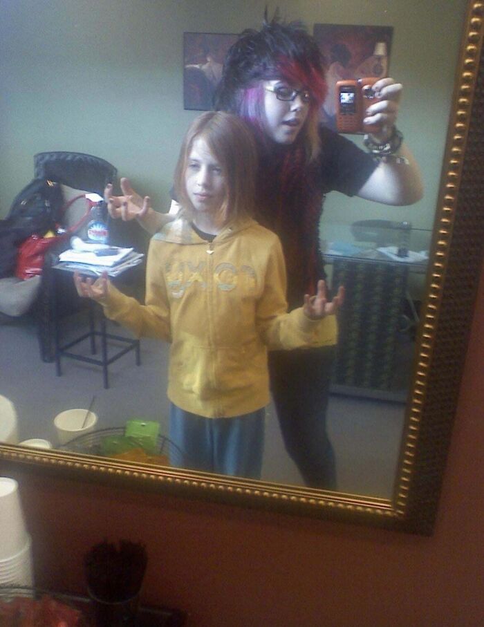 Two people with emo hairstyles and hand gestures pose in front of a mirror during their blunder years.