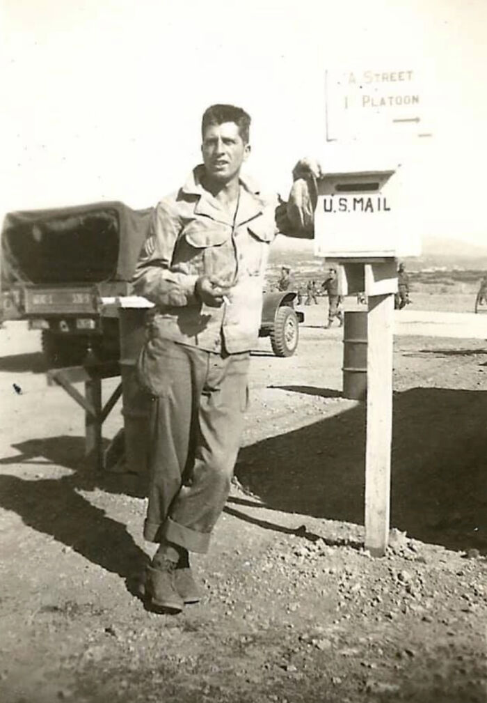 Soldier in uniform leaning on a U.S. Mailbox in a dusty military camp, an old image from fascinating history collection.