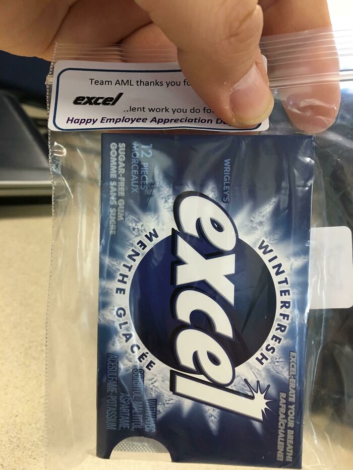A hand holding a plastic bag containing a pack of Excel gum with a note for employee appreciation, showcasing company gifts.