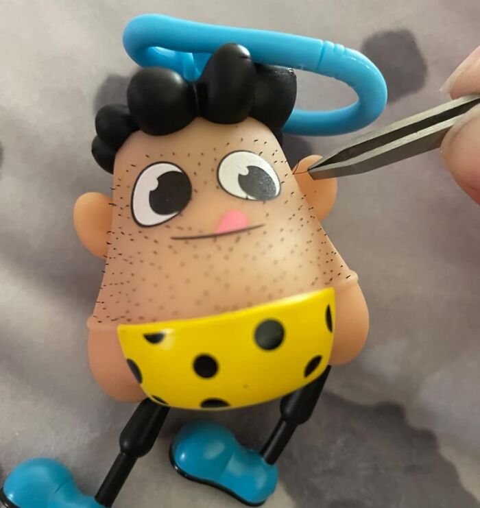 Weirdest gifts: quirky toy with hair stubble, being plucked with tweezers, features polka-dot shorts and a playful design.