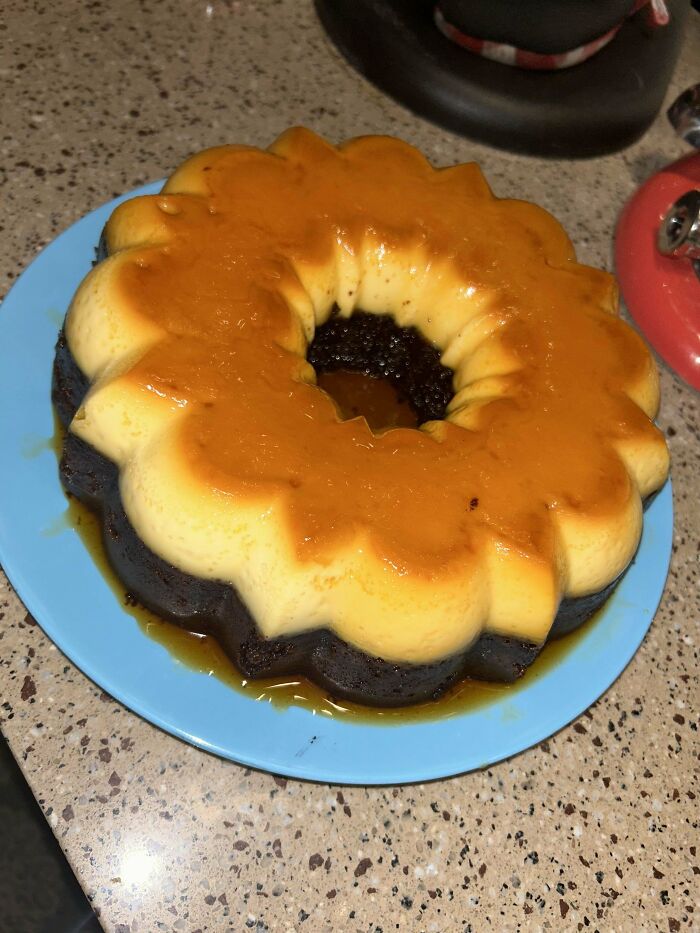 A beautifully crafted flan-cake hybrid on a blue plate, showcasing bakers' culinary concoctions.