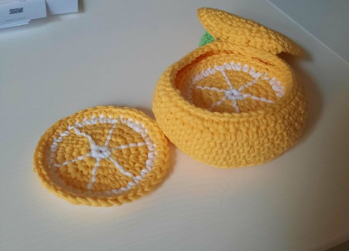 Yellow crochet container with lid and matching coaster, showcasing detailed stitch work as a crochet masterpiece.