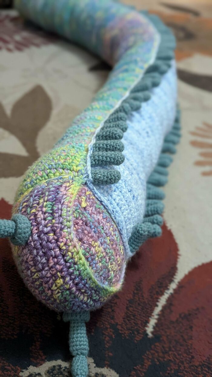 Crochet DIY project featuring a colorful, textured caterpillar design on a patterned surface.