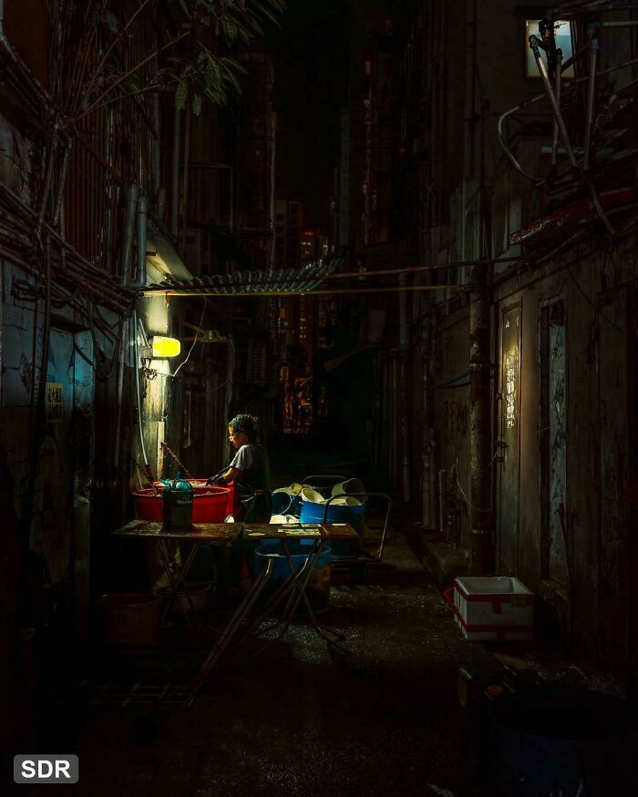 A person illuminated by a streetlight in a narrow alley, creating an accidental Renaissance painting effect.